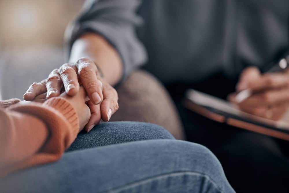 Closeup hands and support in therapy conversation and grief with compassion empathy or support zoom hand or female with sadness therapist or communication for solutions mental health or stress