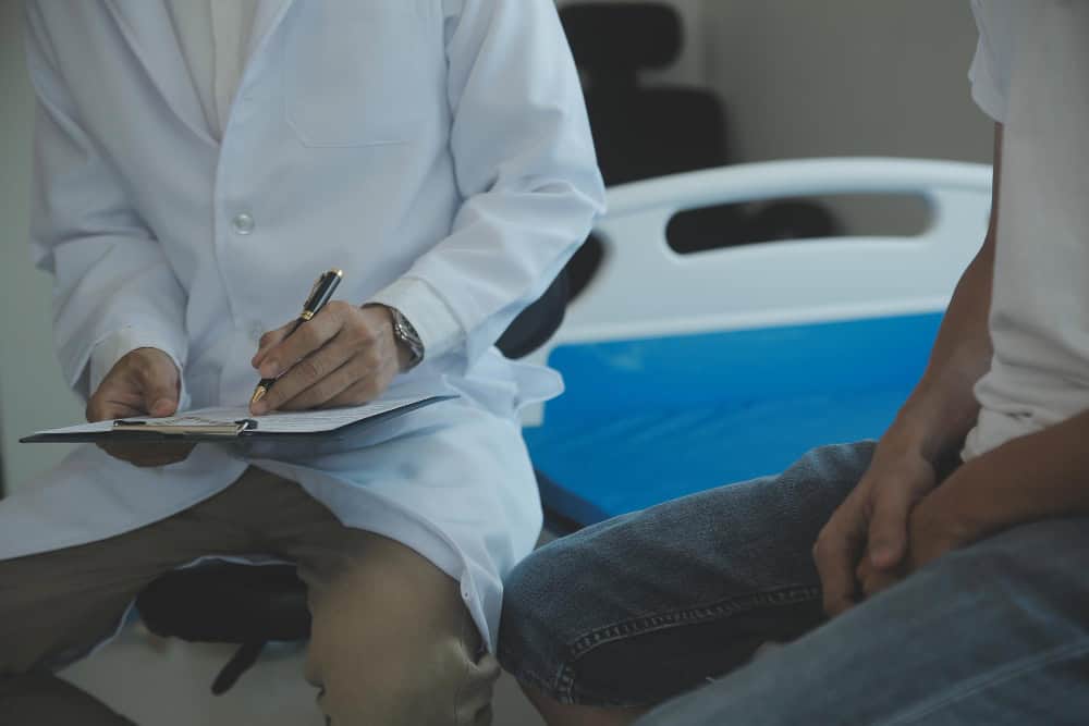 Doctor or physical therapist examines back pain and spinal area to give advice within the rehabilitation center