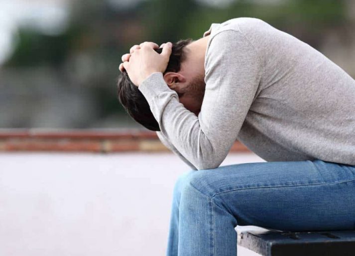 Man sitting with a stressed expression while dealing with MDMA addiction.